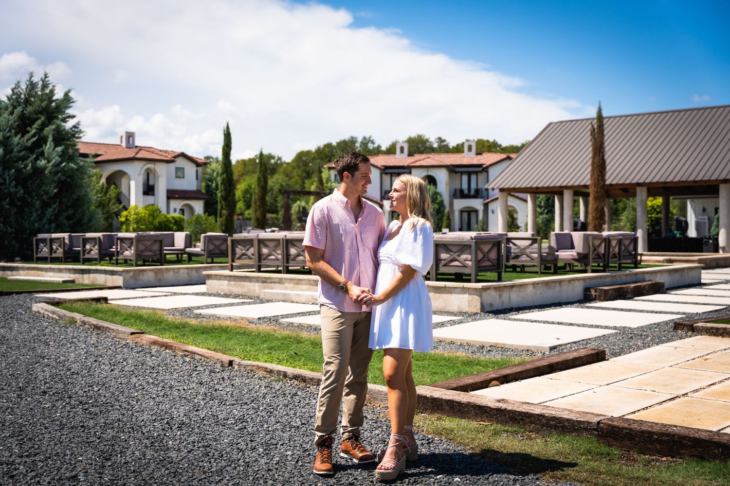 A couple stands together at a winery with beautiful architecture in the background.