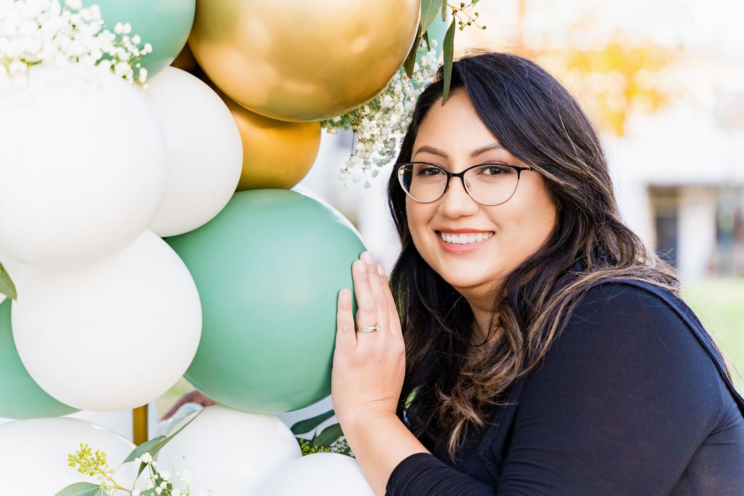 Festive balloon arch with mint green, gold and white balloons decorating an outdoor celebration.