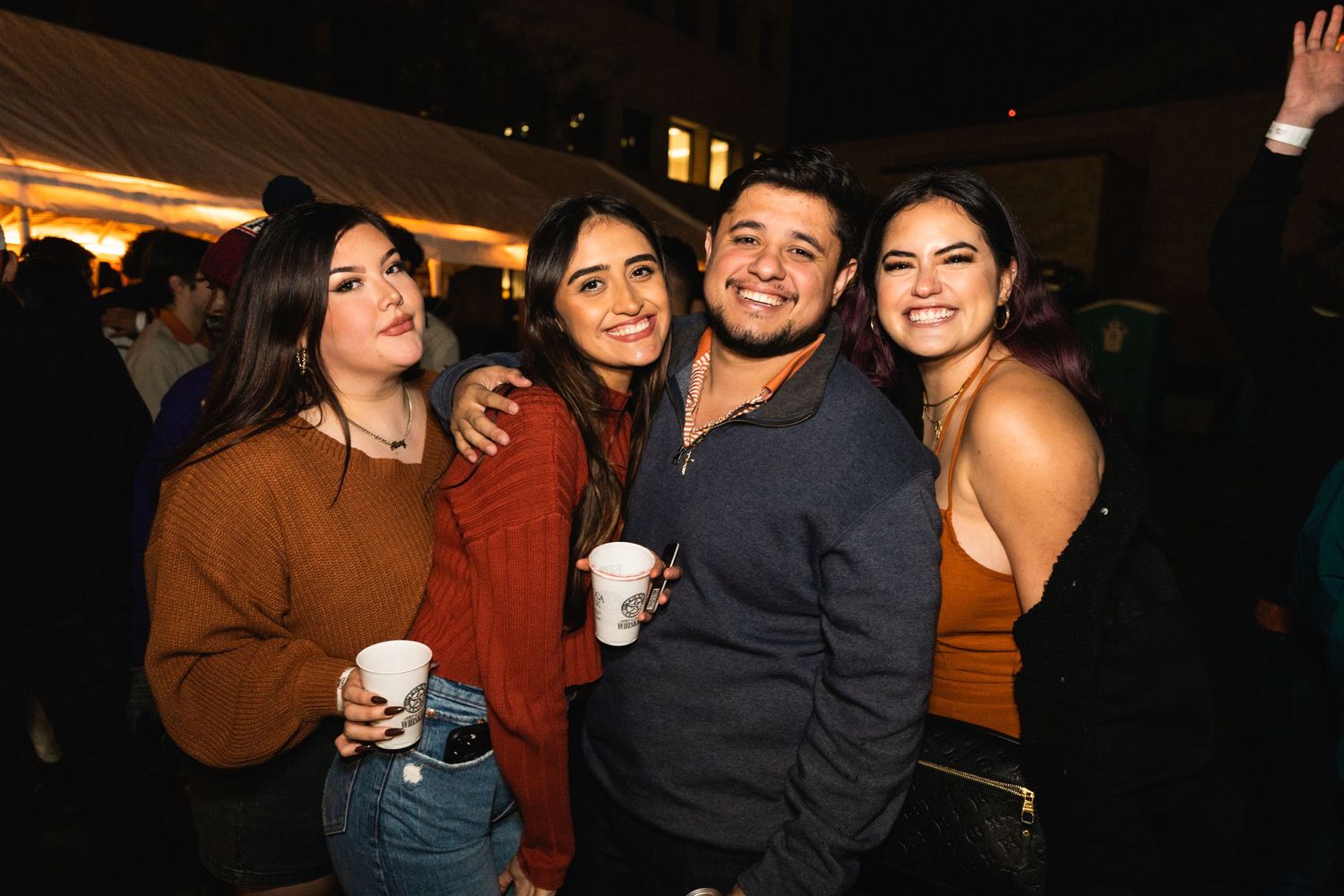 Group of friends smiling together at an outdoor evening gathering.