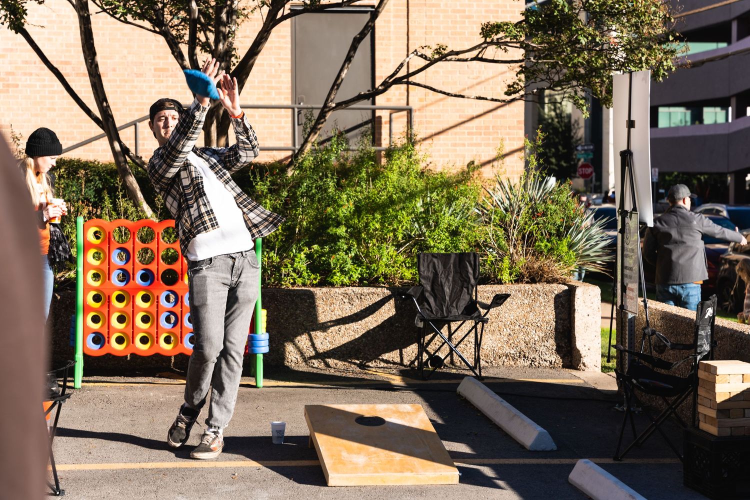 Person playing an outdoor carnival game with large connect-four style setup.