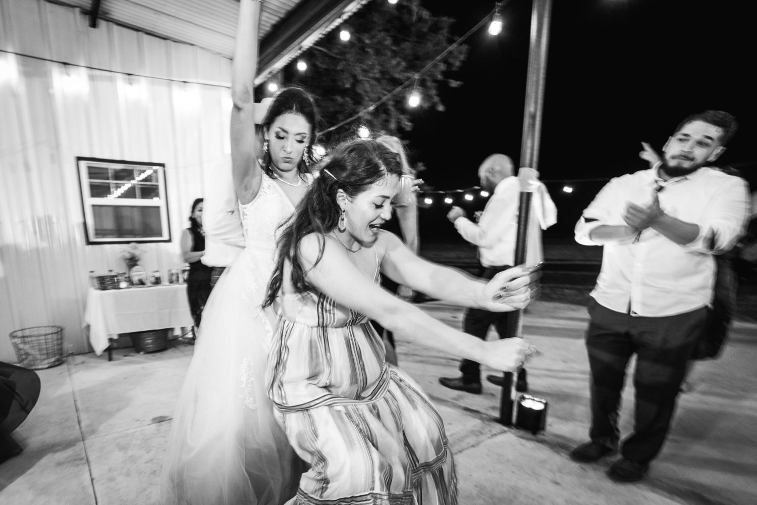 Black and white photo of guests dancing and celebrating at a wedding reception.