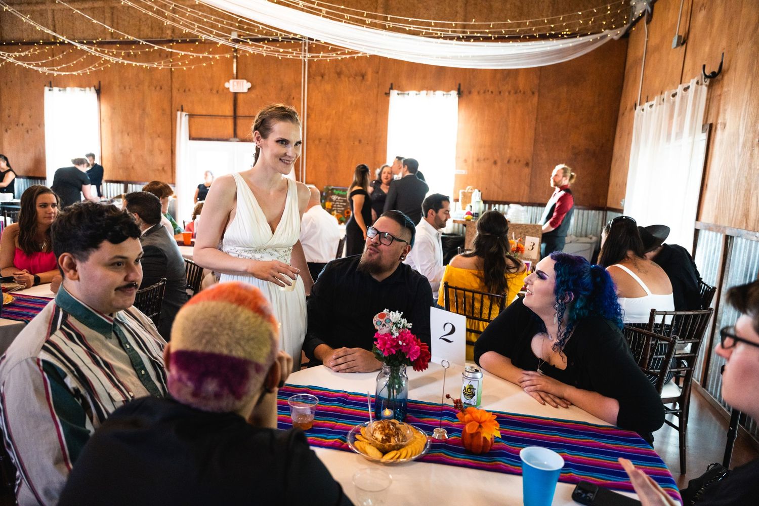 Wedding reception scene in a rustic wooden barn with decorated tables and guests gathered for celebration.