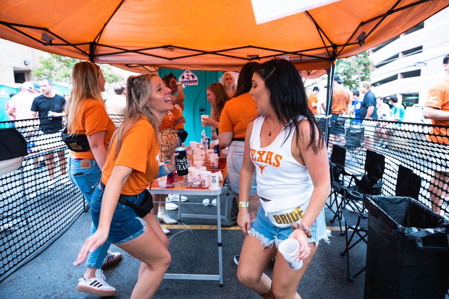 Friends gathering and socializing at an outdoor drink booth under an orange canopy.
