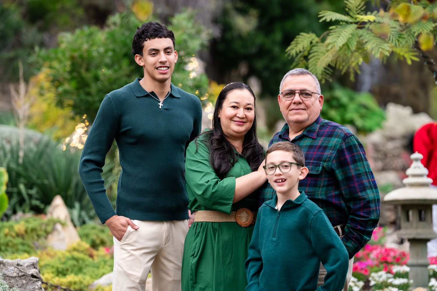 Family members sharing joyful moments together in a garden setting wearing coordinated green and plaid outfits.