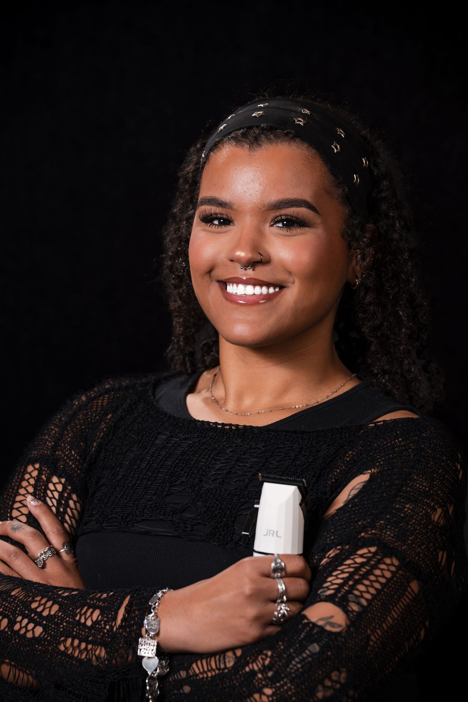 Professional studio portrait in black lace dress against dark background with dramatic lighting and warm smile.