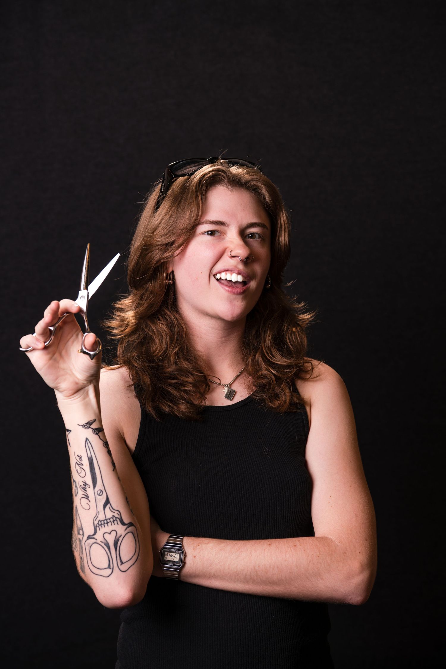 Woman in black top smiles while cutting her own brown hair against dark background in series of photos.