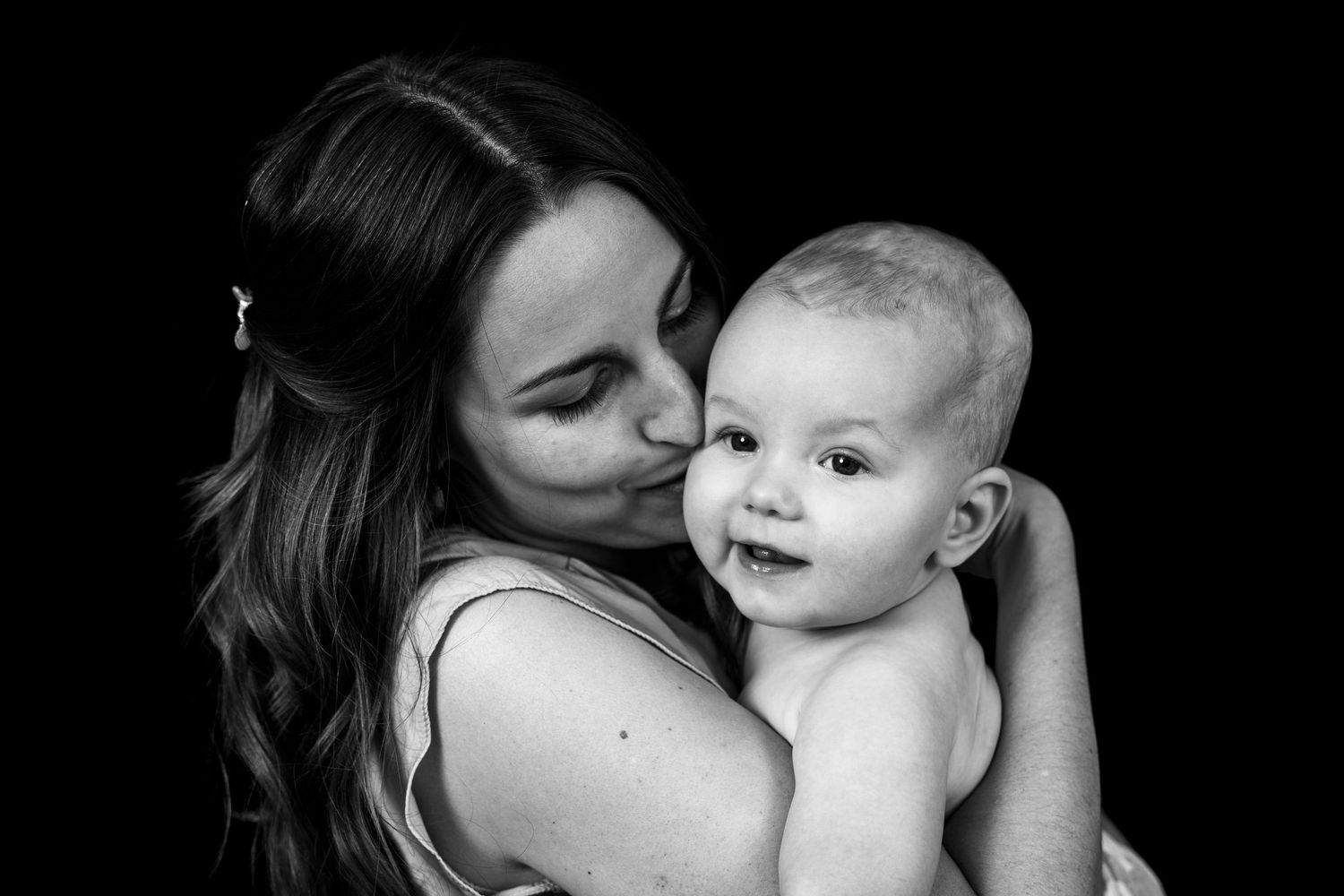 A series of six black and white photos showing tender moments between a parent and baby in intimate poses.