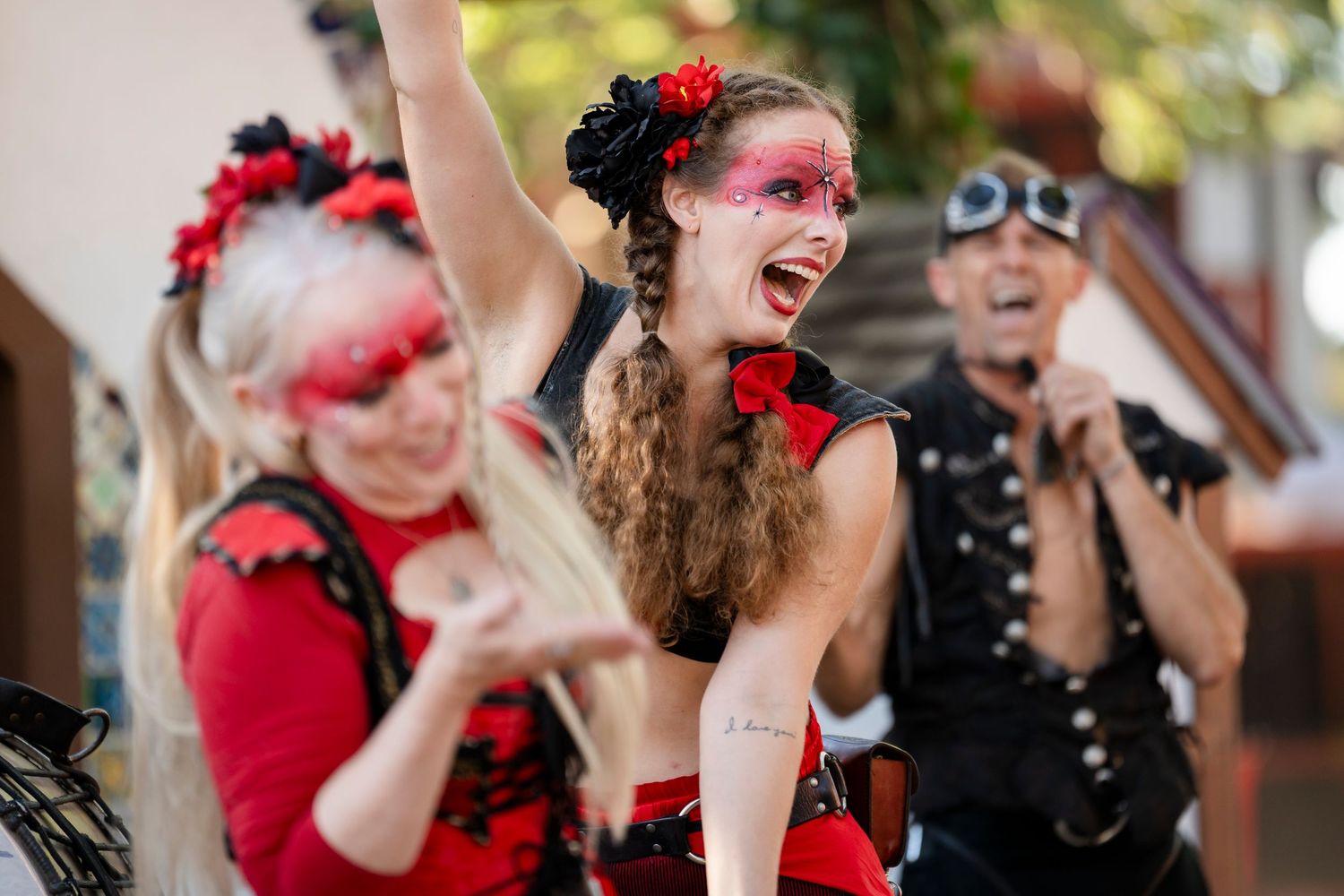 A group in red and black outfits laughs together during a festive outdoor celebration.