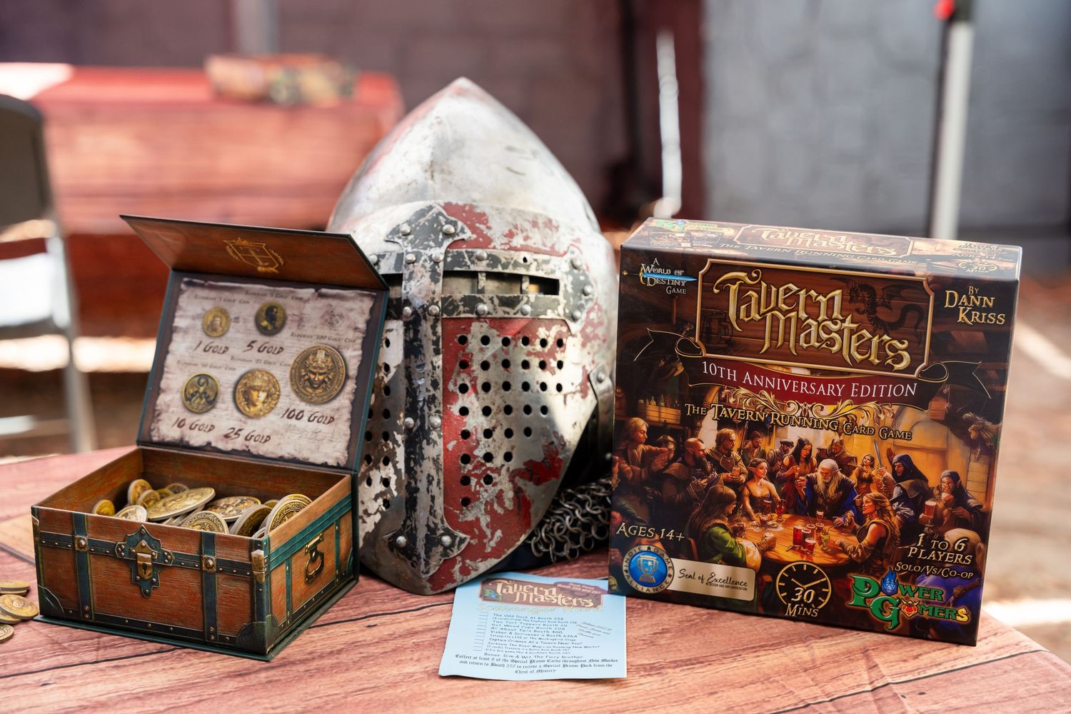 A collection of board game boxes and accessories displayed on a wooden table showing fantasy and adventure themed games.