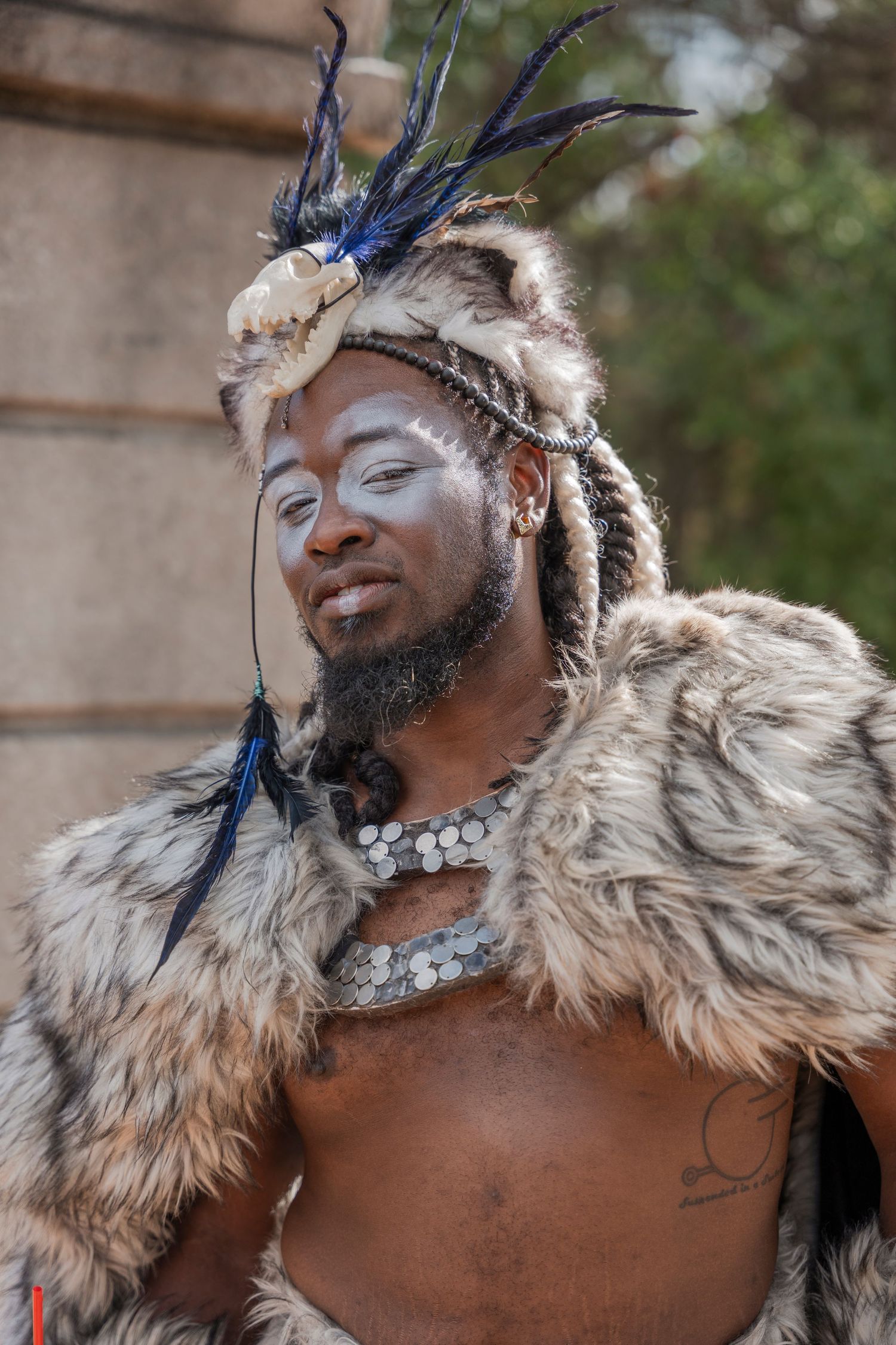 Festival performer in tribal-inspired costume with fur cape and feathered headdress.