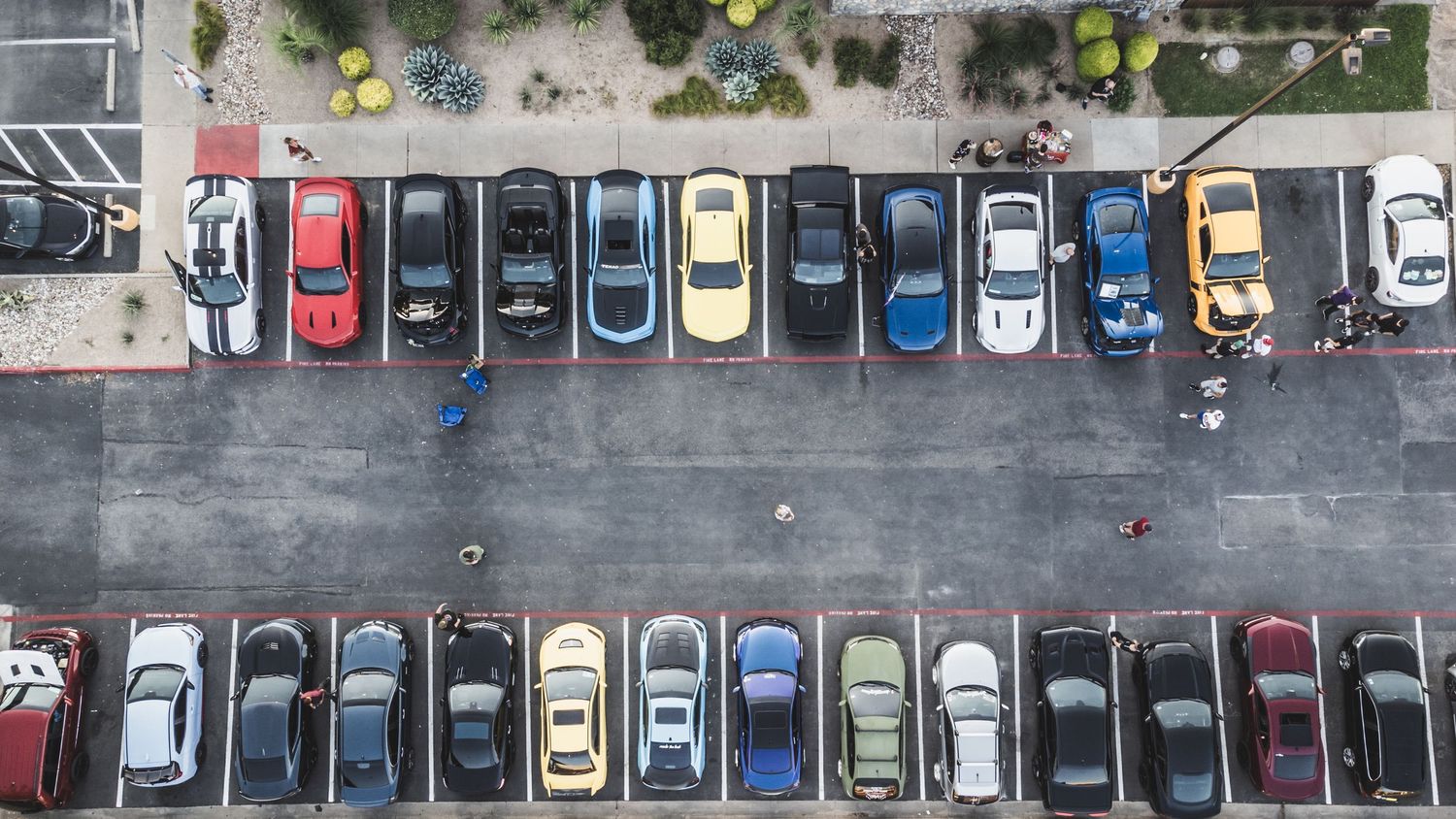 Birds eye view of parking lot filled with various cars at automotive gathering.