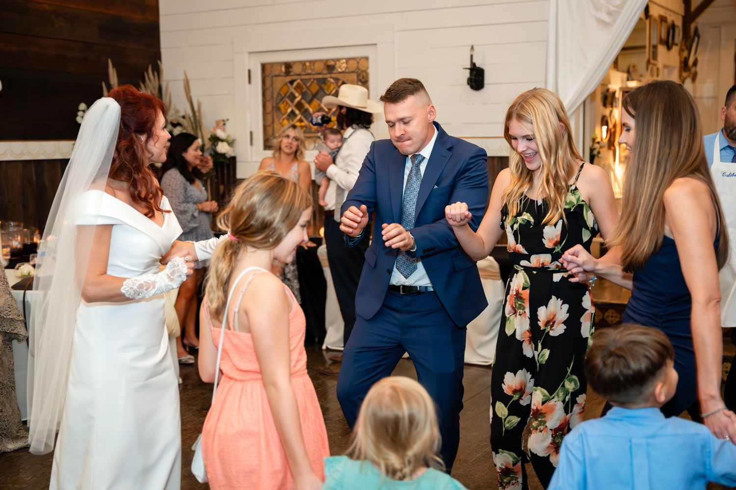 Wedding party gathered together during reception with children in colorful attire.