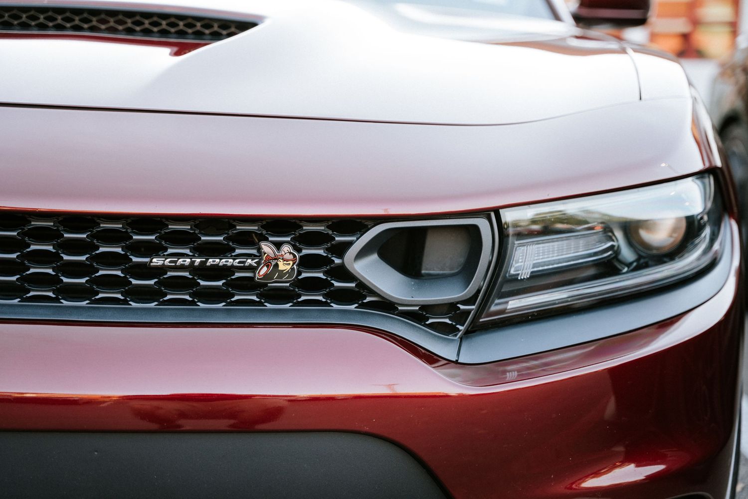Close-up detail of red Dodge Charger headlight and grille design.