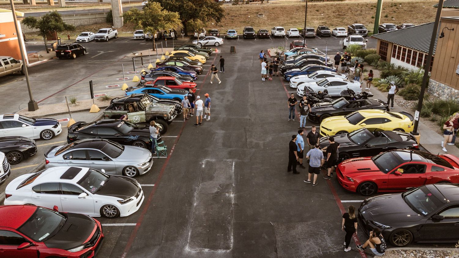 High angle shot of classic and modern cars gathered for an evening car meet.