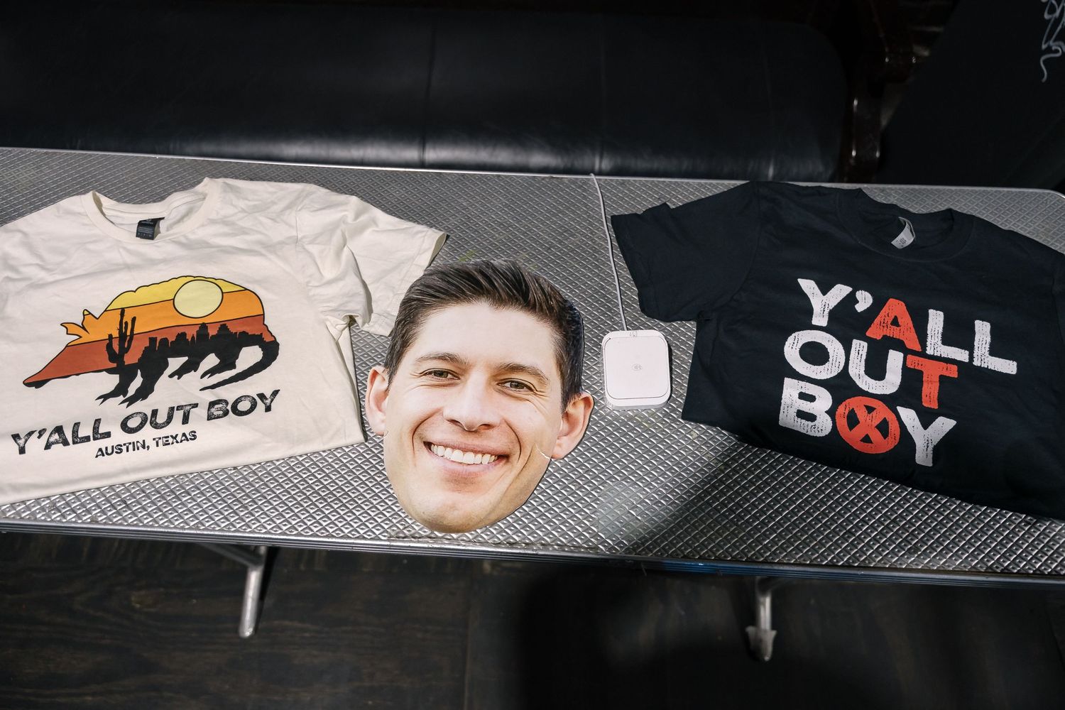 Merchandise display featuring two t-shirts with band designs laid out on dark surface.