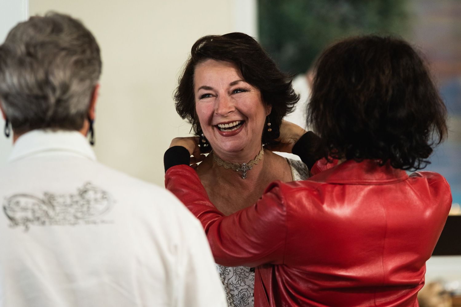 A joyful moment captured with a woman in a red satin jacket laughing during a celebration.
