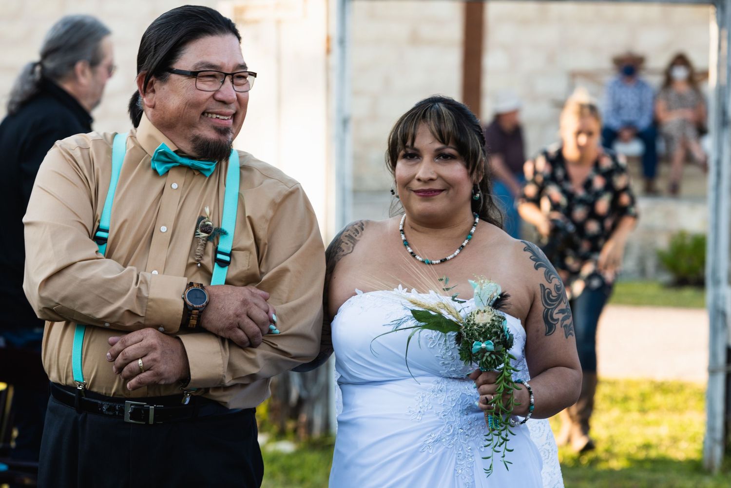 Wedding couple during outdoor ceremony with rustic stone backdrop.