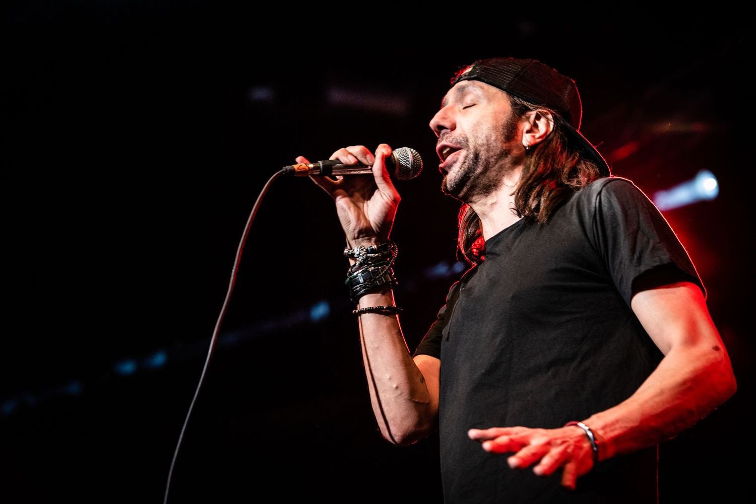 Passionate vocalist performing on stage with microphone against dark background.