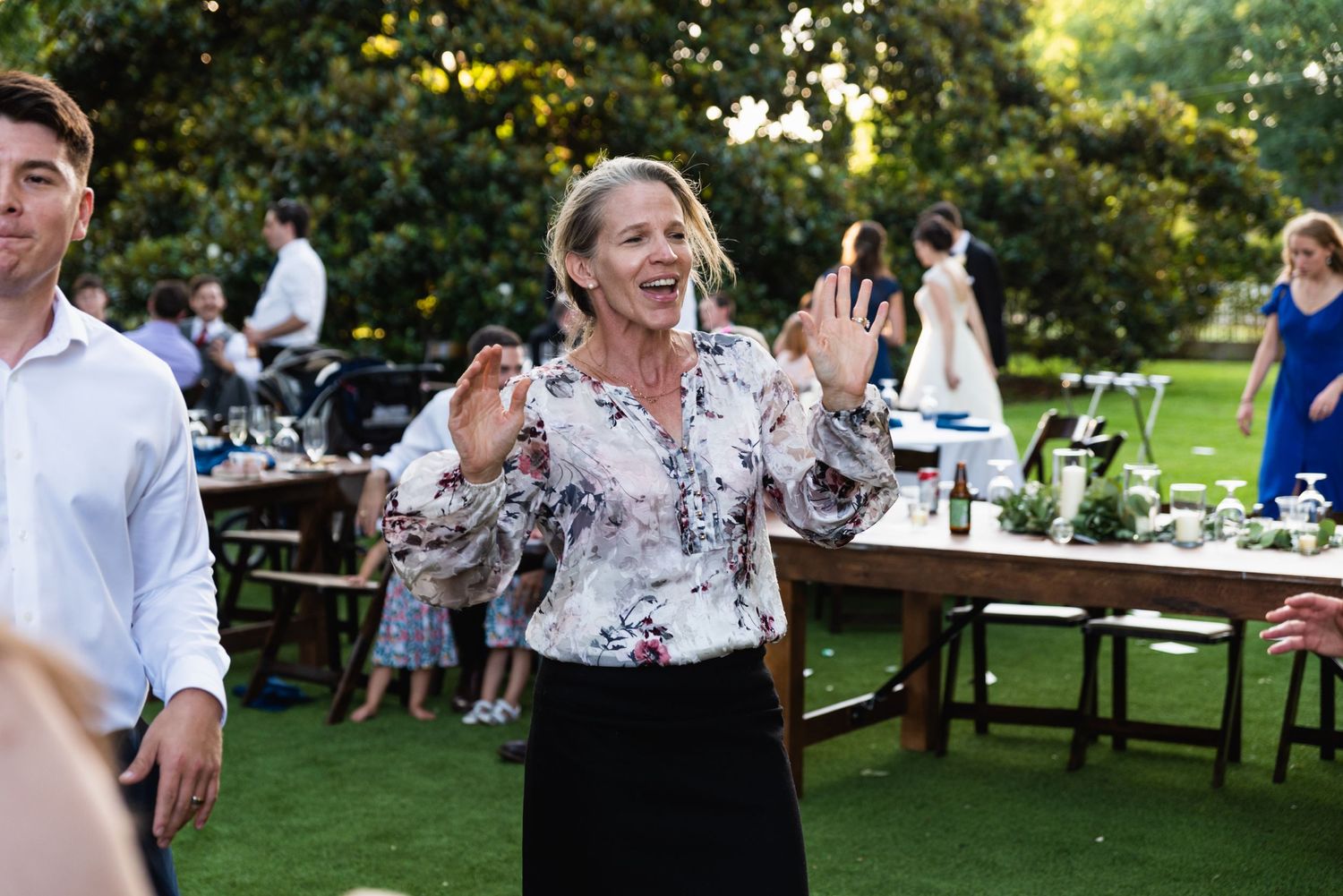 Guest dancing enthusiastically during an outdoor garden reception with tables in background.