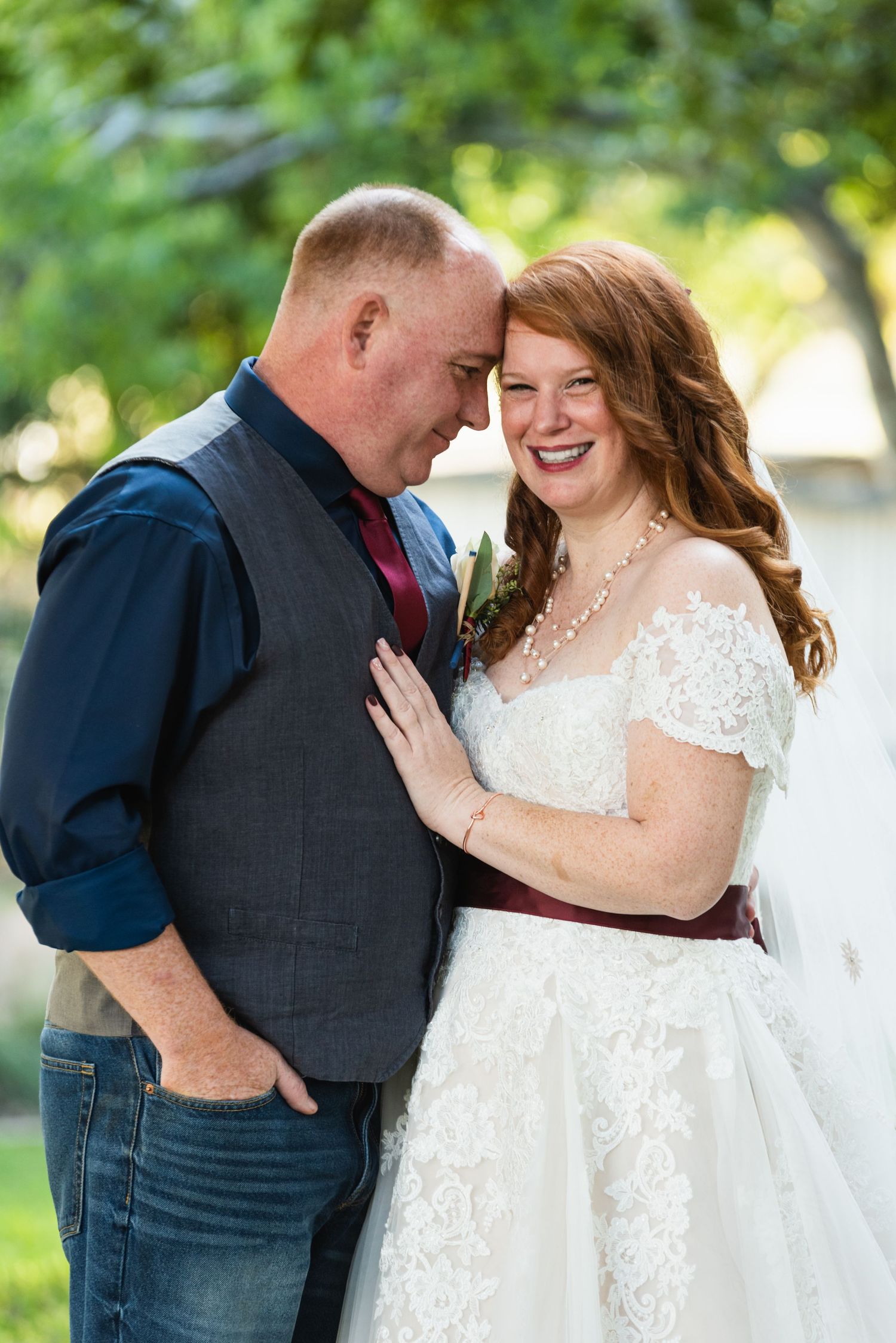 Intimate outdoor wedding portrait with sunlit greenery in the background.