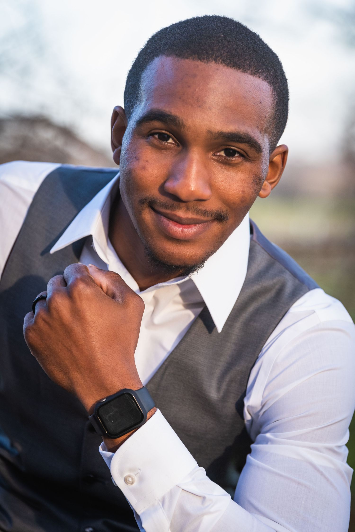 Portrait of elegantly dressed man in vest and white shirt wearing a smart watch.