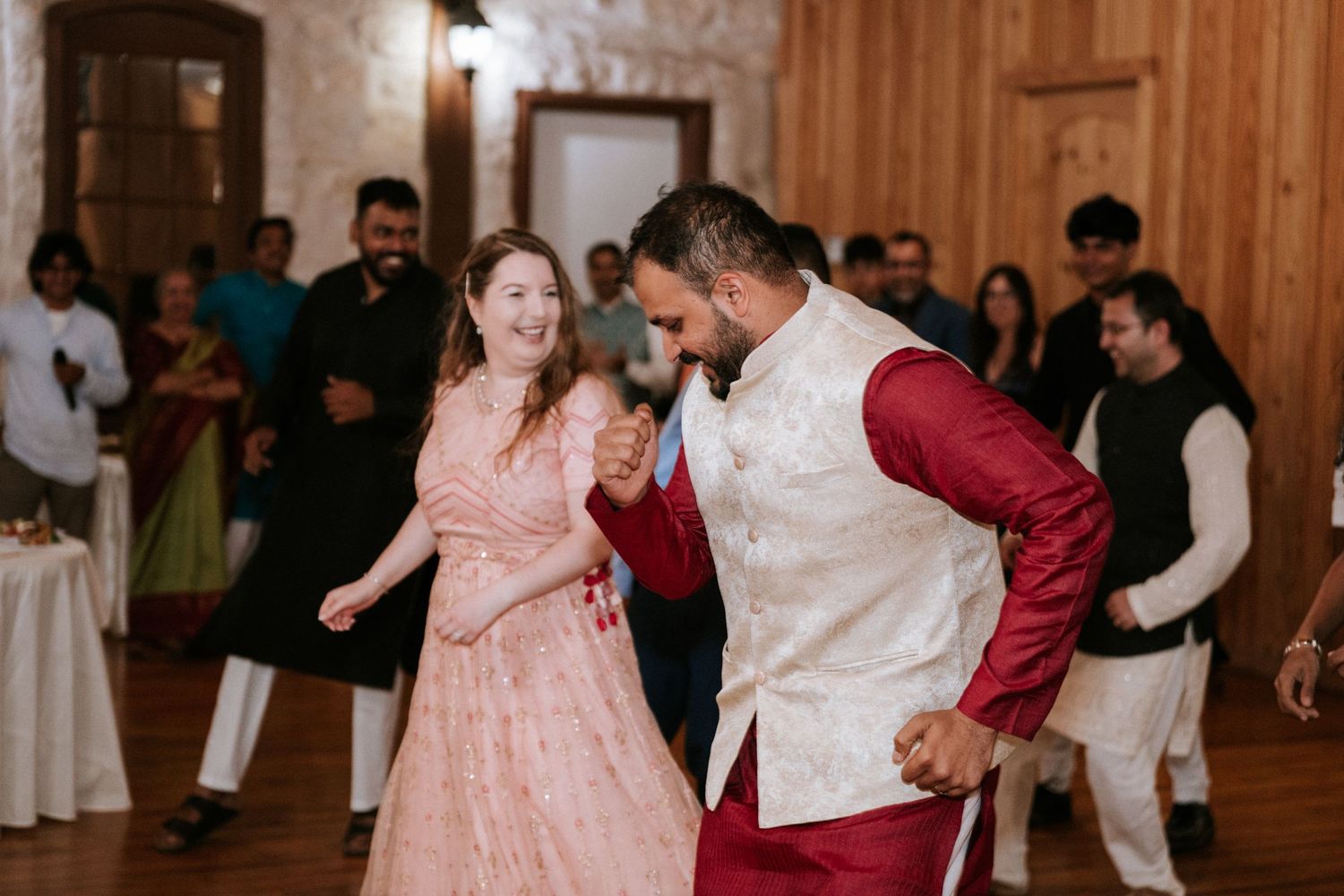 Couples dancing together at a wedding reception in a rustic wooden venue.