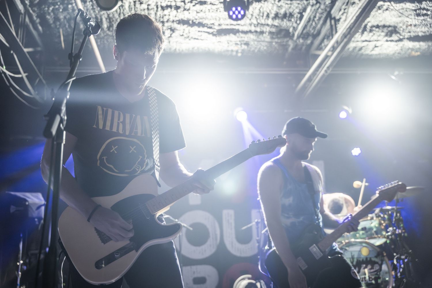 Musicians perform on stage with dramatic backlit silhouettes and bright stage lighting.