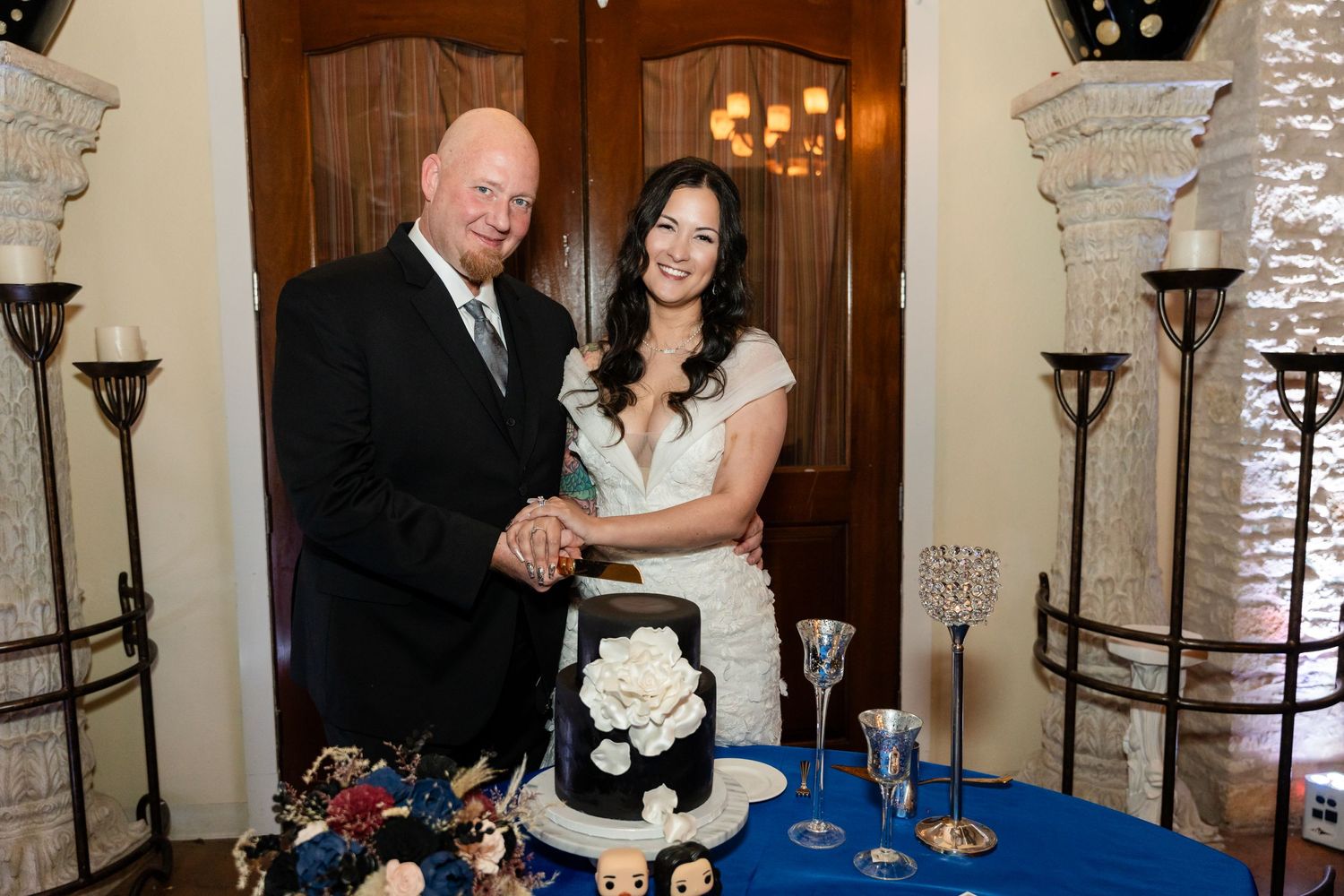 Newlyweds cutting their wedding cake together at an elegant reception venue.