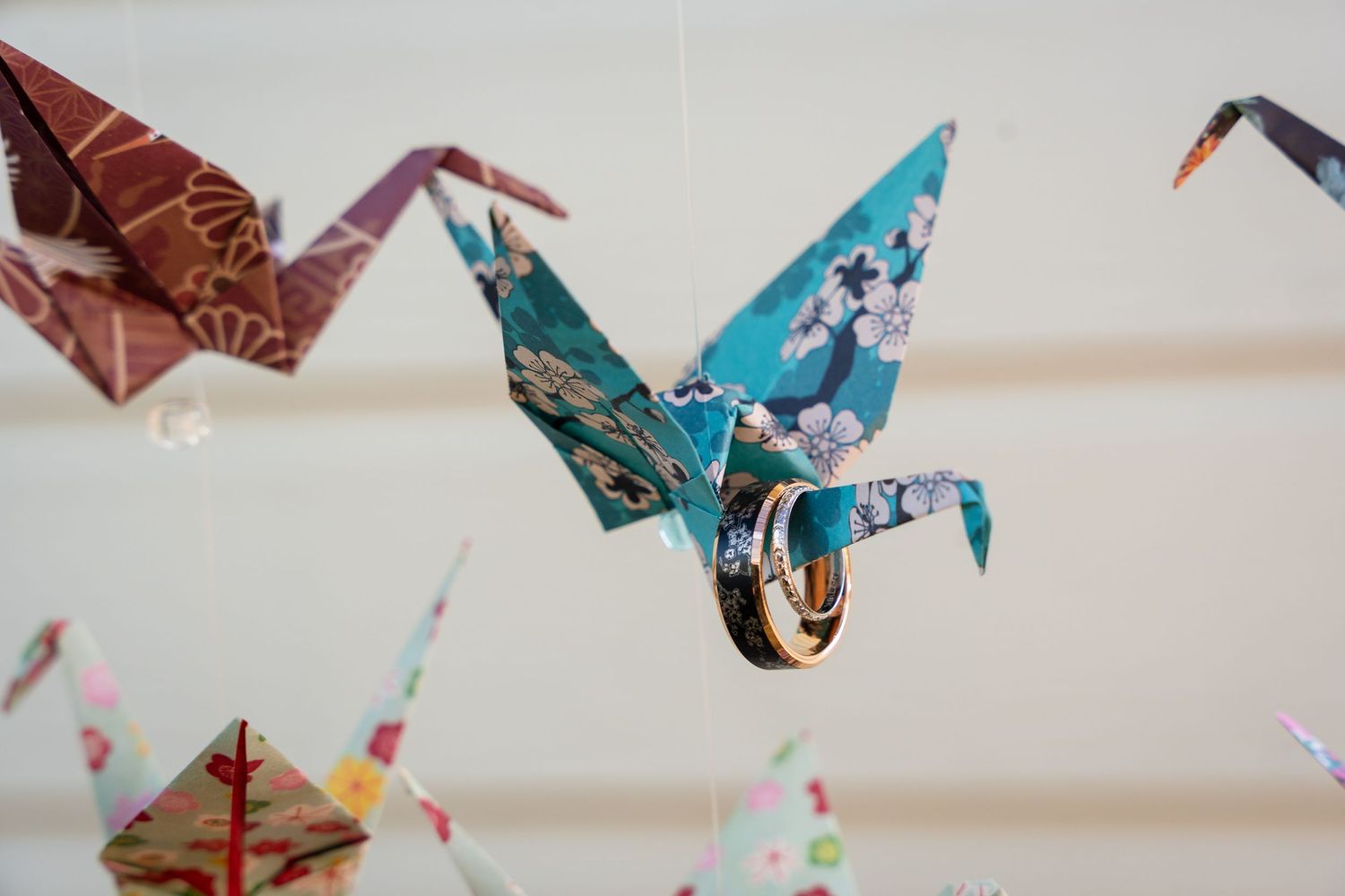 Colorful origami paper cranes hanging from strings in an artistic display.