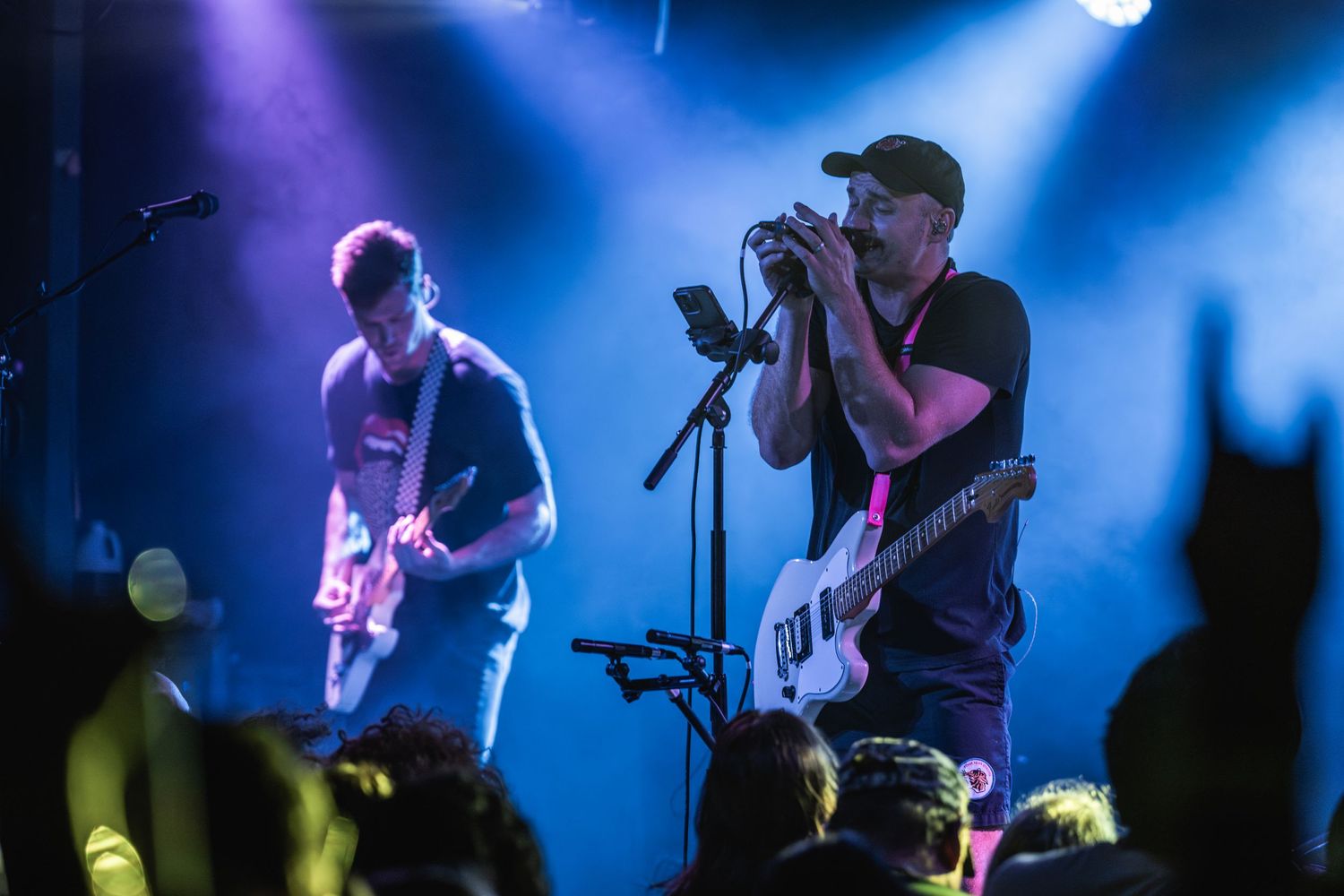 Musicians performing on stage with dramatic blue lighting and silhouetted instruments.