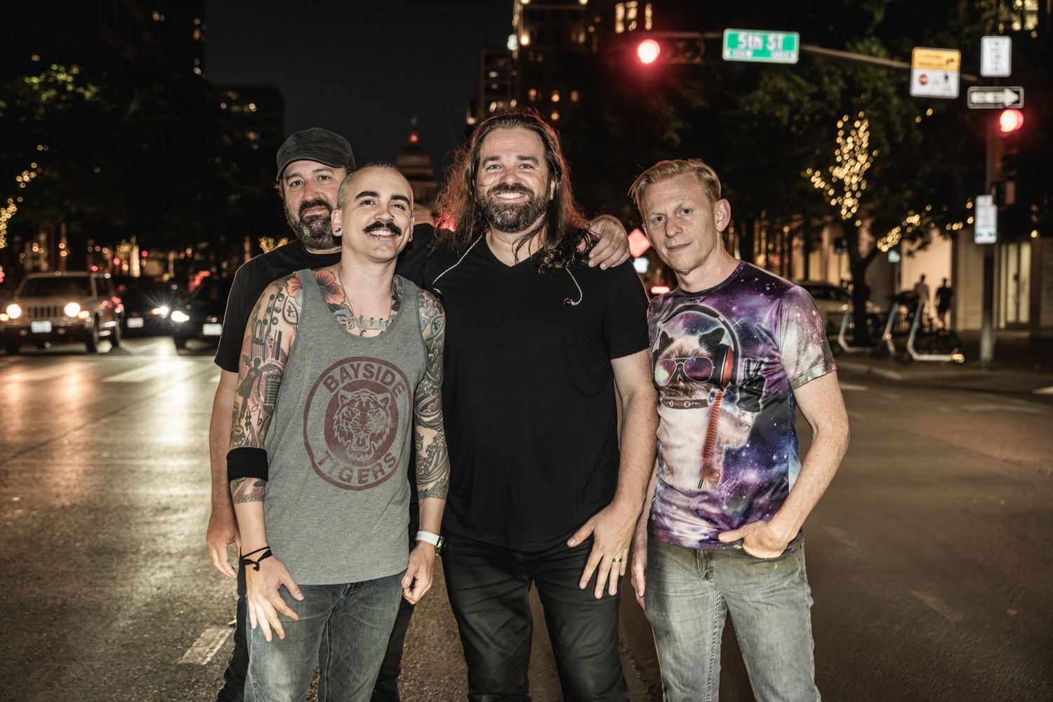 Musicians standing together on city street at night with urban lighting.
