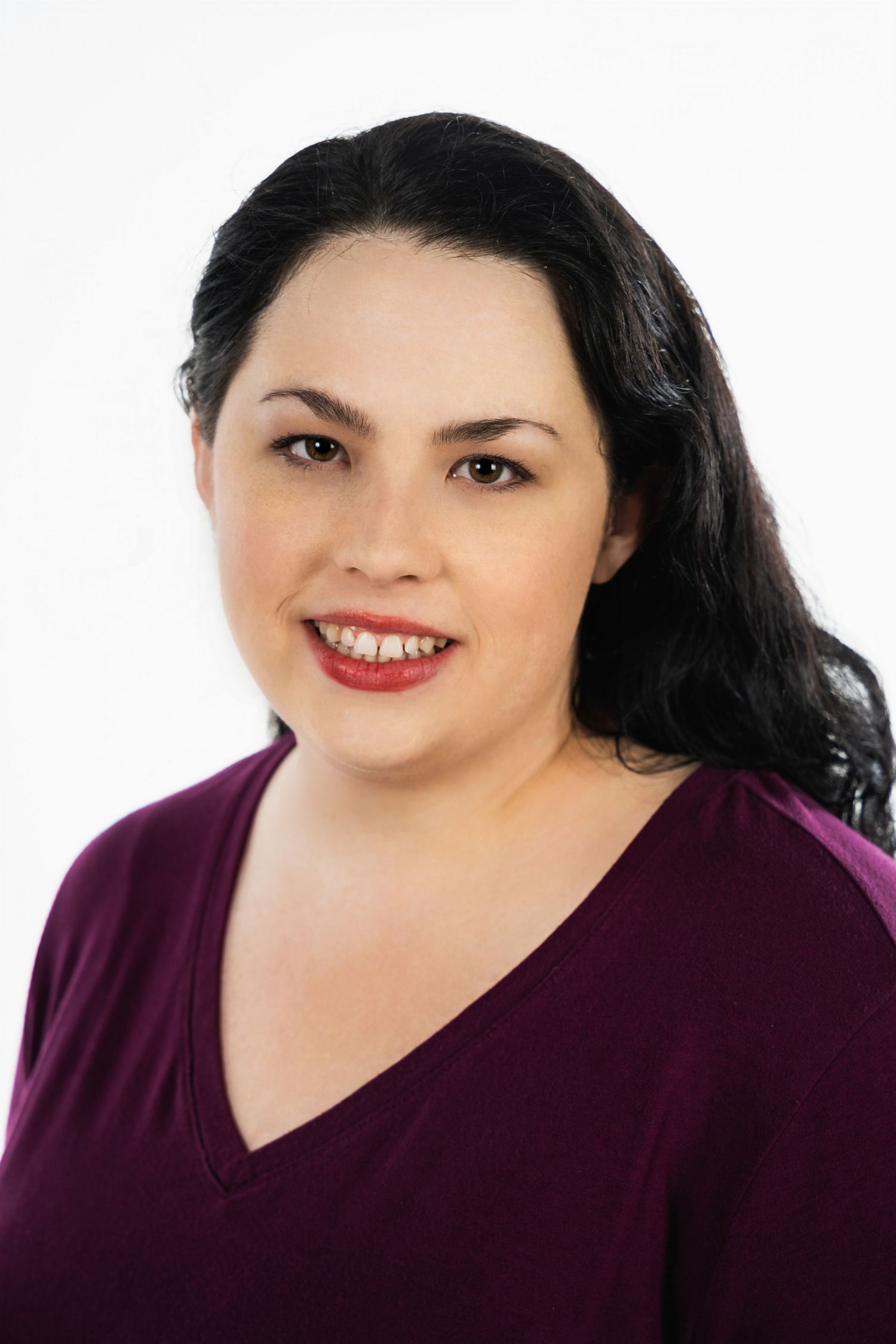 Professional headshot of a woman in a purple v-neck top against a white background.