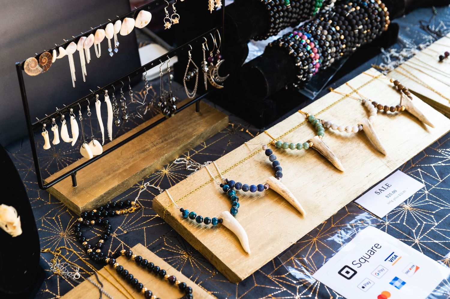Handmade jewelry and beaded accessories arranged on wooden display stands.