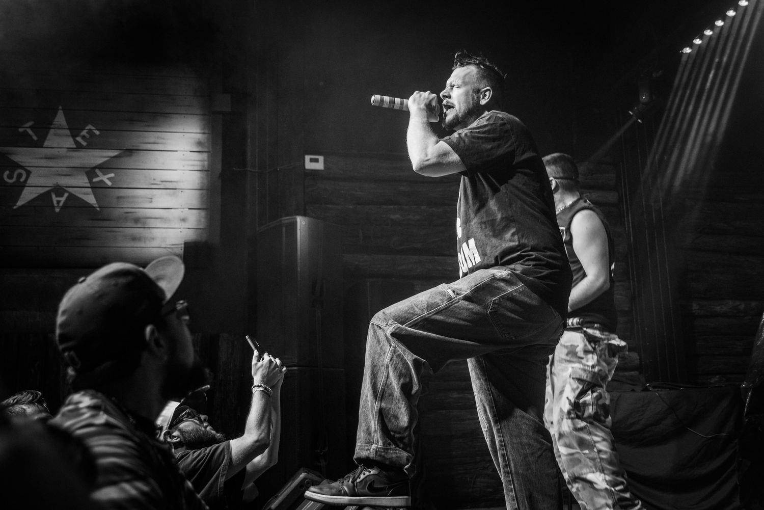 Energetic black and white performance photo showing performer interacting with audience.