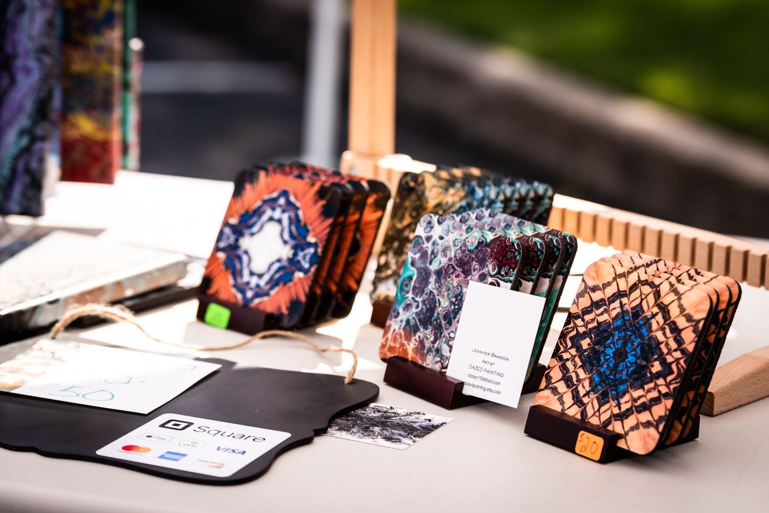 Handcrafted decorative items with geometric patterns displayed on a vendor table at a craft market.