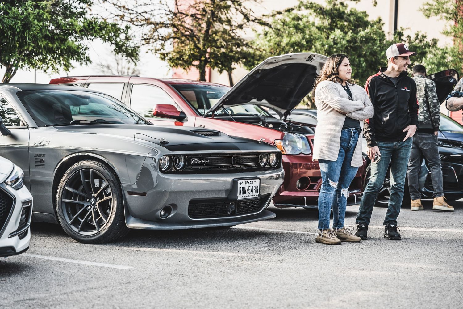 A modified Dodge Challenger with custom wheels and body kit on display at a car meet.