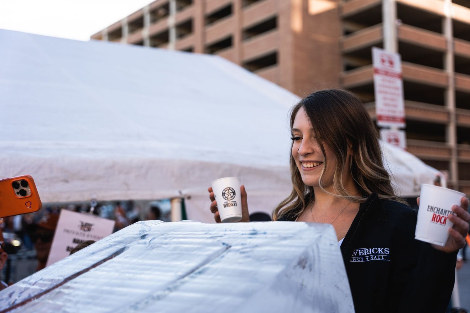 A server in dark attire smiles while working at an outdoor event.