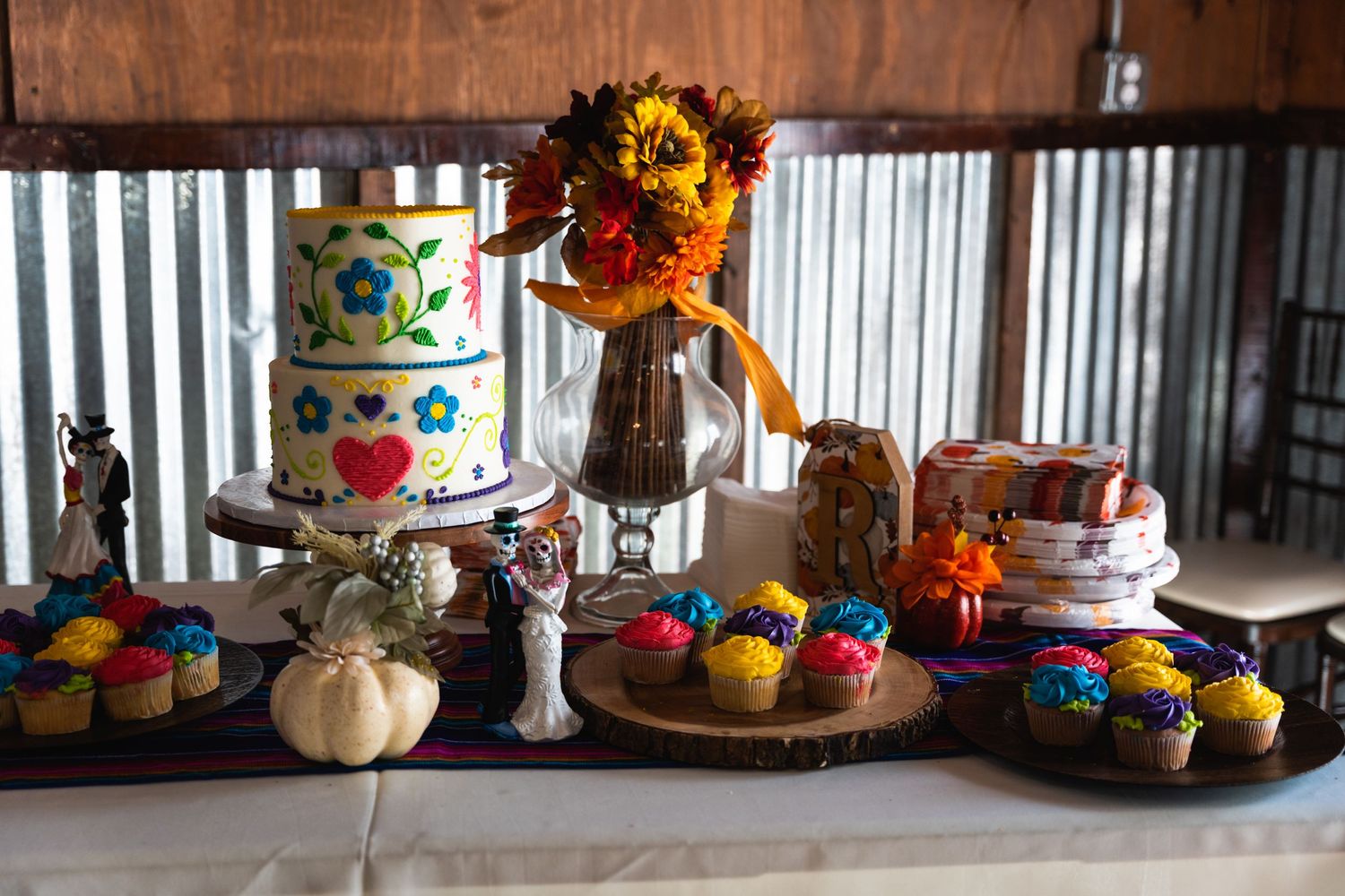Festive dessert table with tiered cakes, sunflowers, and colorful decorations.
