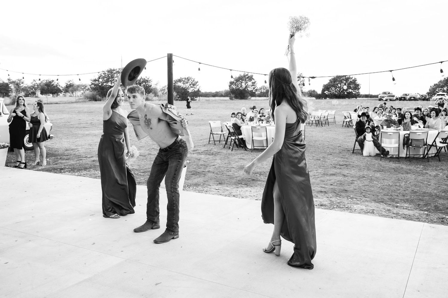 Black and white photo captures guests dancing at outdoor wedding reception.
