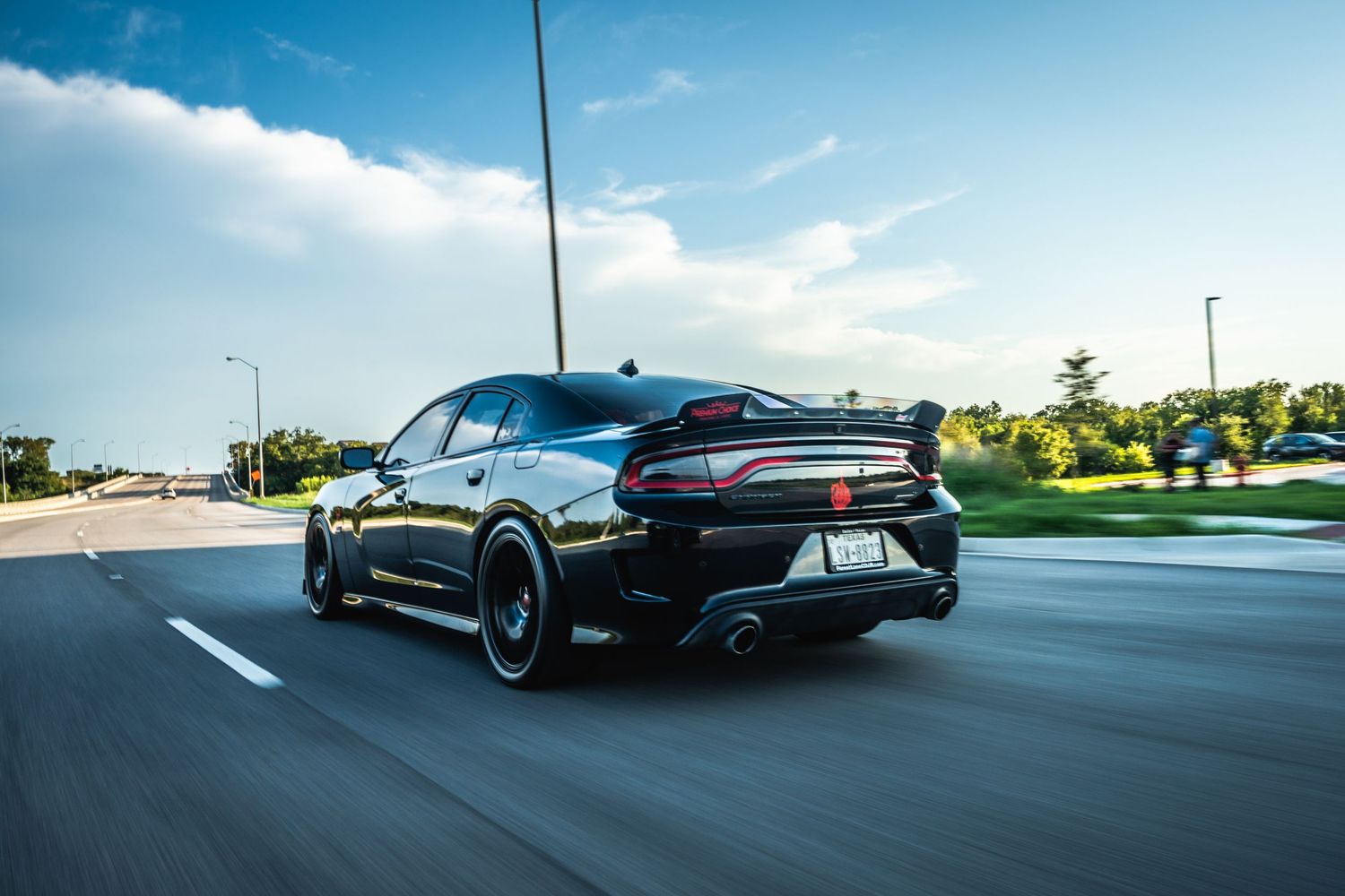 Rear view of black Dodge Charger with custom exhaust and spoiler in motion.