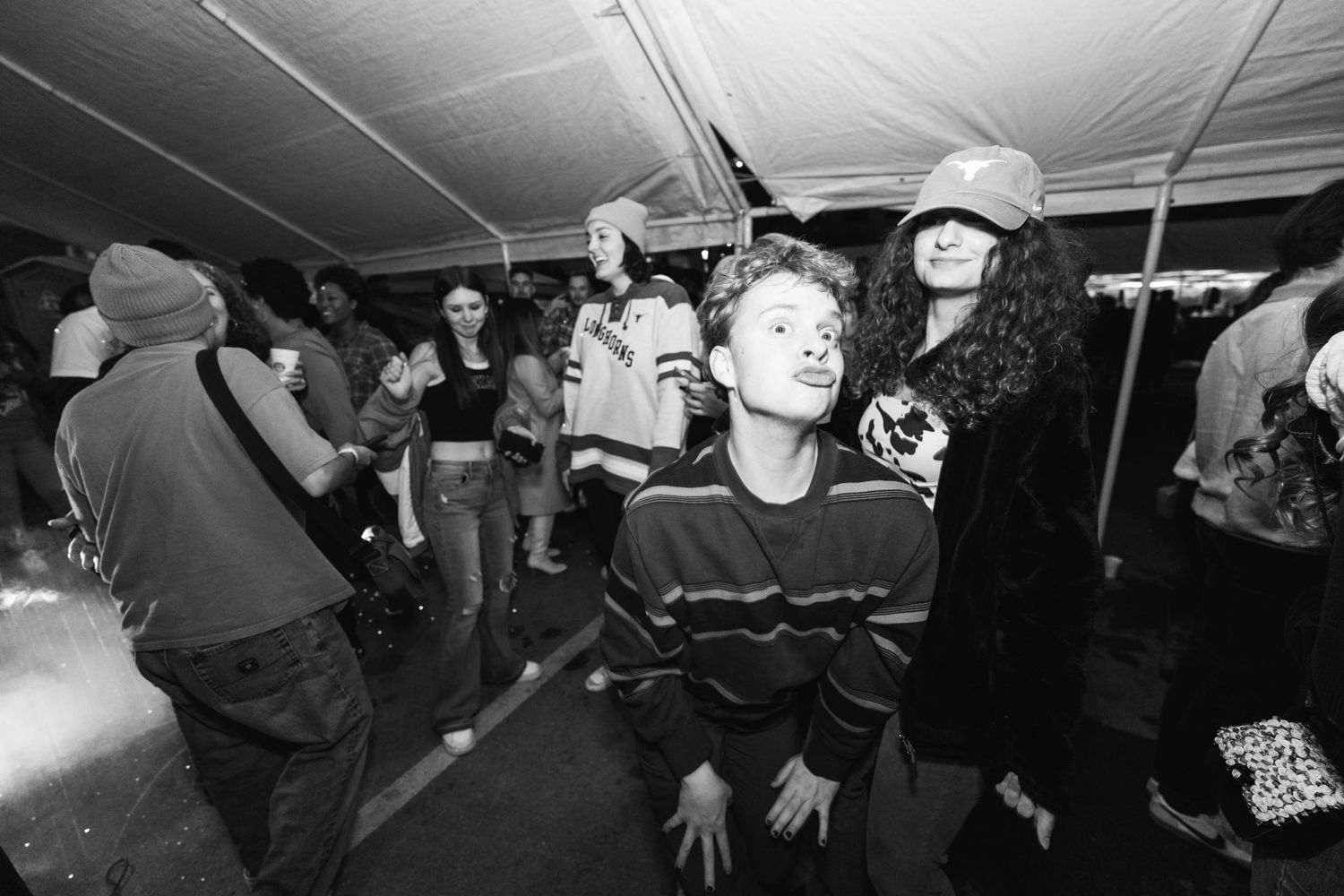 People dancing and enjoying themselves at a dimly lit indoor party space.