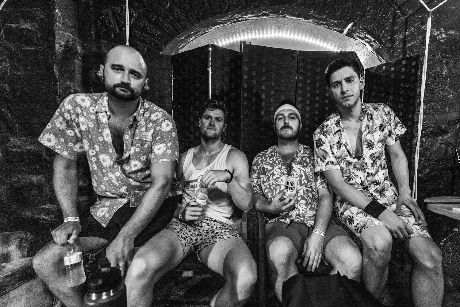 Group of friends in matching floral shirts enjoying drinks outdoors.