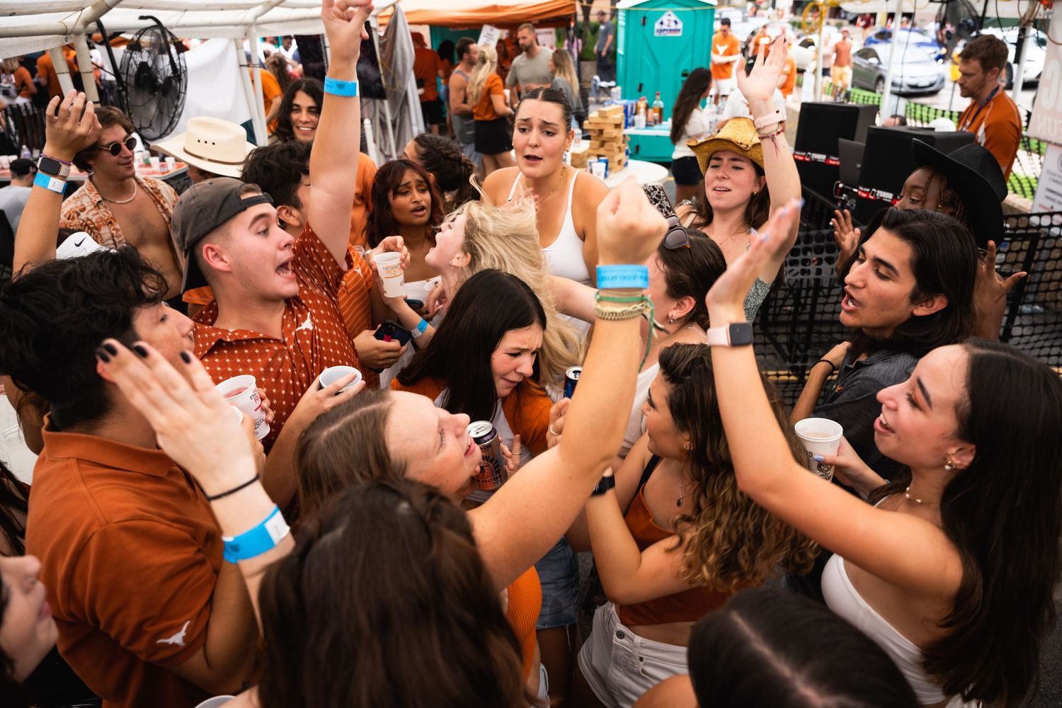 Large group of festive attendees cheering and raising drinks together at an outdoor party.