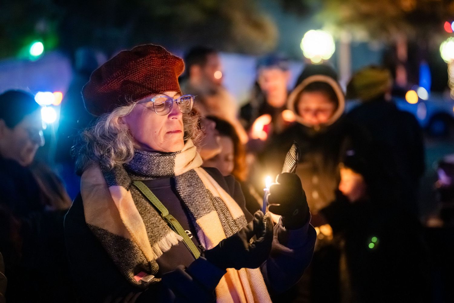 People hold illuminated candles during a nighttime vigil or memorial service.