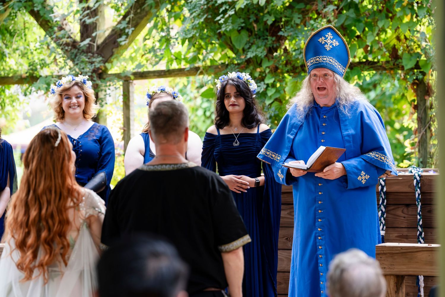 People in blue uniforms gather outdoors under trees during a casual event or gathering.