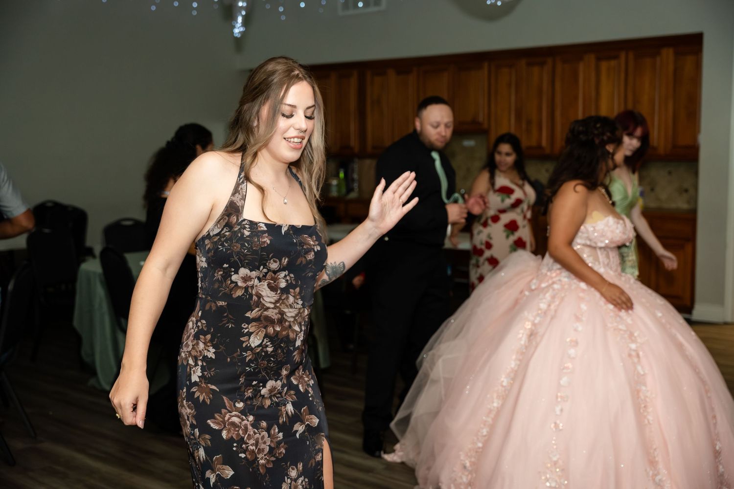 Guests dancing joyfully at a formal celebration with a woman in a pink ball gown.