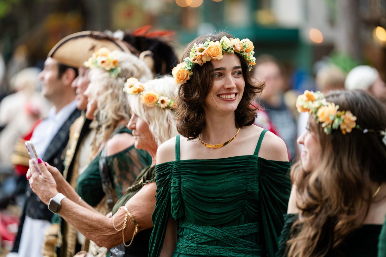 Wedding party members in emerald green dresses dance and celebrate during an outdoor reception celebration.