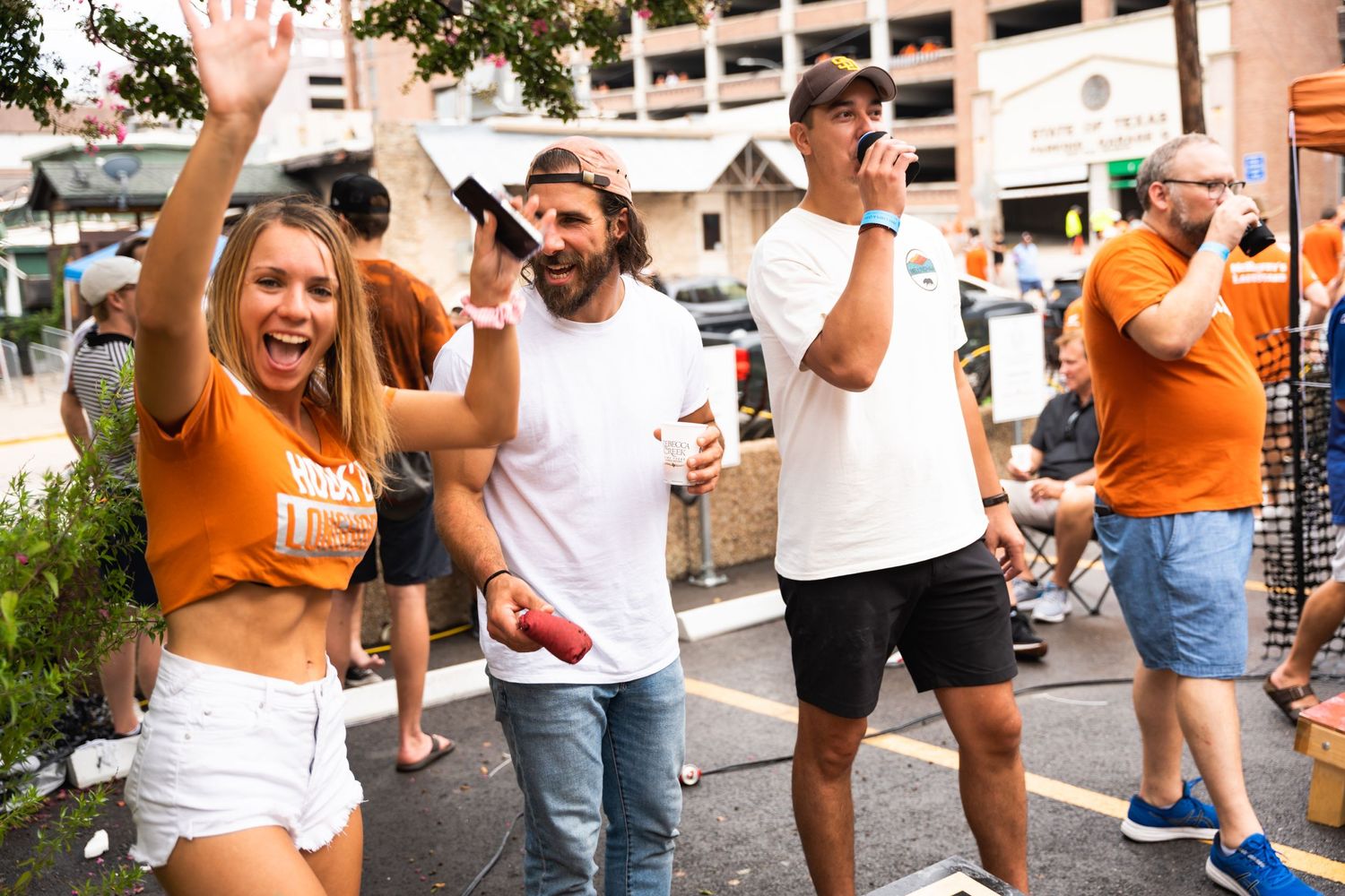Excited crowd cheers during outdoor tailgate celebration.