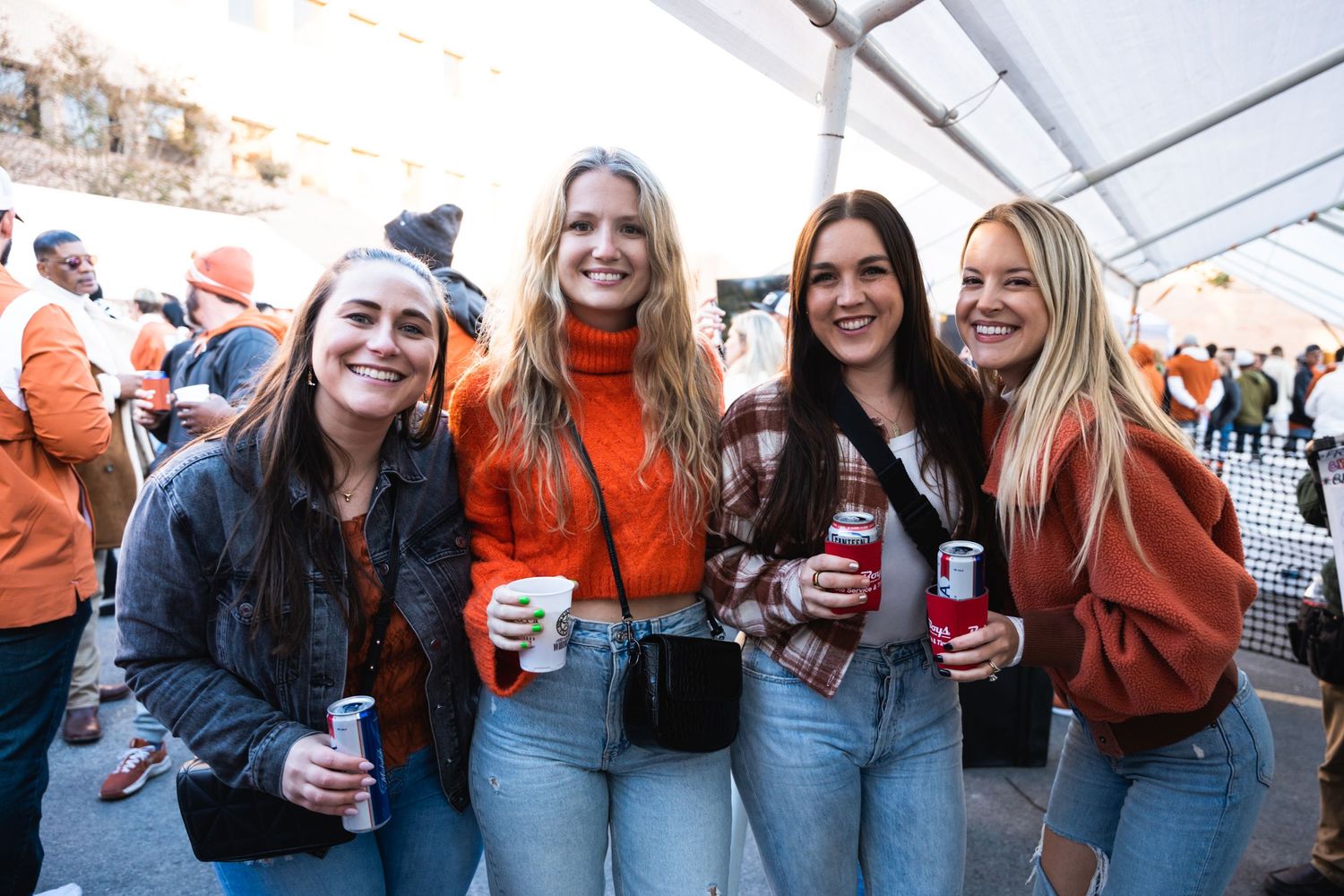 Group of friends in casual attire enjoying drinks at an outdoor gathering.