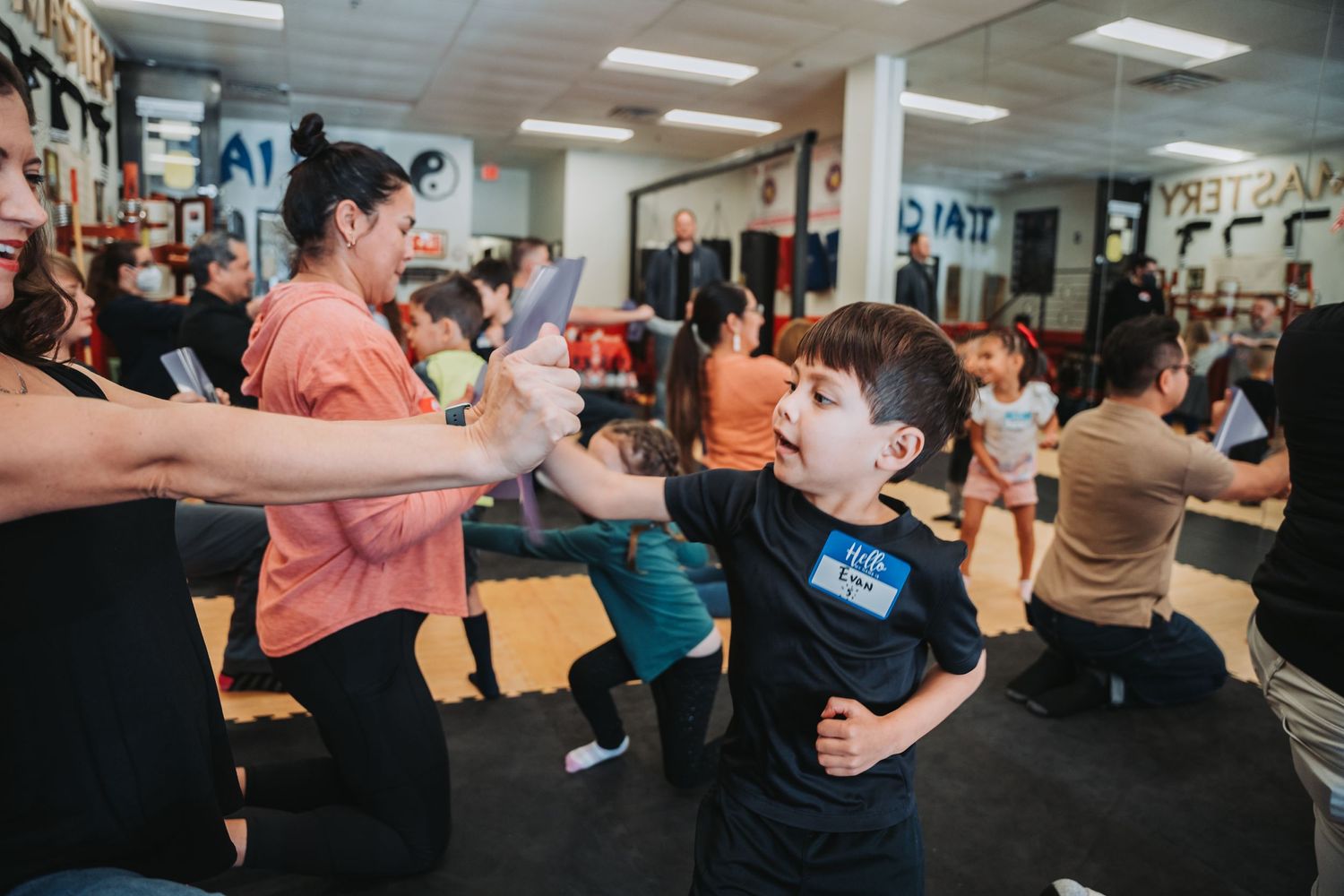 Student practices martial arts techniques with instructor using training pads.